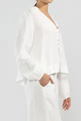 Pantalón blanco de lino italiano, de pierna ancha, con cintura elástica ajustable con cordón, bolsillos laterales y cortes redondeados en los laterales.