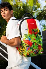 Mochila Sprayground con estampado de aves tropicales y vegetación selvática. Tiene un bolsillo con cremallera en la parte superior, dos bolsillos laterales con velcro, un bolsillo trasero con velcro, un bolsillo trasero con cremallera, correa para carro, espalda acolchada y transpirable, correas acolchadas y transpirables, cierre con cremallera de doble sentido, asa y accesorios de metal color oro pulido. El interior está forrado con poliéster con el logo de la marca, tiene un compartimento principal espacioso, dos bolsillos con cremallera, un compartimento acolchado para laptop.