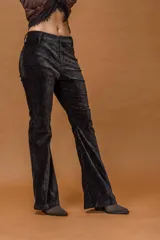 Pantalón de corte oxford confeccionado en pana negra con textura aterciopelada. Presenta un ajuste en la cadera y muslos, con una leve apertura desde la rodilla hacia el ruedo.