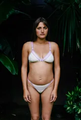 Bombacha semivedetina color blanco con detalles de tiras y ribetes en color lila, confeccionada con laterales regulables mediante arandelas metálicas.
