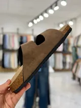 Sandalias de dos tiras negras con hebillas metálicas ajustables, plantilla anatómica y suela plana.