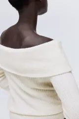 Top de punto acanalado con escote off-the-shoulder y mangas largas. Presenta un diseño ajustado con cuello vuelto y textura acanalada en toda la prenda.