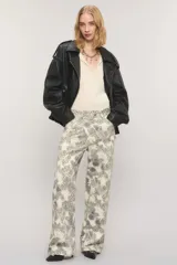 Pantalón de tiro medio y calce holgado, confeccionado en 100% algodón de peso medio con un estampado exclusivo de diseño ornamental en tonos blanco y gris oscuro. Cuenta con una cartera asimétrica cruzada en la cintura, bolsillos y sutiles desgastes manuales con pequeñas roturas localizadas.