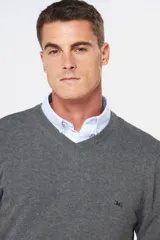 Suéter de tejido fino color azul marino, con cuello en V y manga larga. Presenta un pequeño logo bordado en el pecho.