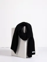 Bufanda de tejido de punto acanalado en color negro, con etiqueta de marca en uno de sus extremos.