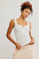 Remera sin mangas blanca de tejido texturado y elastizado, con escote henley y botonadura frontal parcial. Calce ajustado y largo corto.