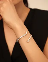 Pulsera abierta de diseño minimalista con acabado en plata, inspirada en la forma de un clavo con detalle de resorte central y grabado de la marca.