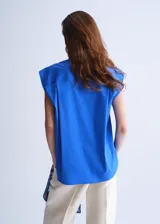 Camisa de popelín color azul, de diseño oversize y sin mangas, con cuello camisero, bolsillo parche delantero y cierre frontal con botones.