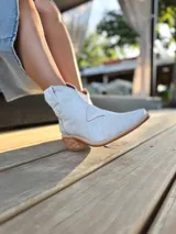 Botas texanas de cuero color gris claro, con caña baja, puntera cuadrada y taco de madera.