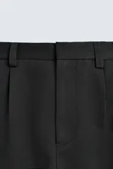 Pantalón de corte wide fit confeccionado en tejido con mezcla de lyocell. Presenta pliegues frontales dobles, bolsillos laterales y bolsillos traseros de vivo. Cierre frontal con cremallera y gancho metálico oculto.