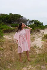 Túnica de corte holgado con estampado a cuadros en tonos rosa y crudo, con cuello redondo y mangas cortas amplias. Incluye cinturón de la misma tela para ajustar a la cintura.