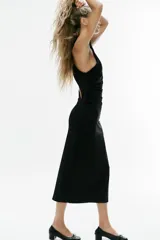 Vestido midi negro de cuello halter con efecto cruzado, espalda con abertura asimétrica y frunces drapeados en el delantero.