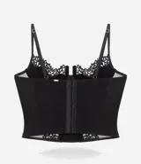 Corset de media copa en color blanco, confeccionado con paneles de poliamida y detalles decorativos de encaje floral en el borde superior y tul en los laterales. Cuenta con tirantes finos ajustables y varillas internas para estructura.