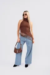 Polera de seda con lycra color blanco, de cuello alto y espalda descubierta. Presenta un diseño asimétrico en la parte inferior con un detalle de encaje sutil en el ruedo.