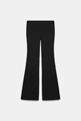 Pantalón flare stretch negro de tiro medio, con cintura elástica y botamanga acampanada.