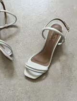 Sandalias de tacón bajo color blanco, con tiras finas y cierre con hebilla.