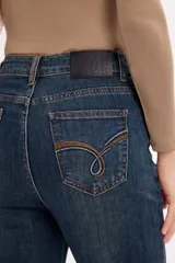 Jean de corte flare con tiro alto, confeccionado en denim azul con costuras laterales marcadas y ruedo desflecado.