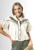 Blusa off white de algodón con cuello mao, mangas cortas globo y cierre frontal de botones. Presenta un canesú destacado con bordado calado en tono verde seco.