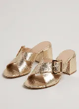 Sandalia de taco ancho color dorado, confeccionada en cuero vacuno, con diseño de tiras cruzadas y hebilla metálica decorativa.