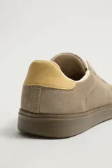 Zapatillas deportivas estilo retro de gamuza color tostado, con suela engomada marrón y detalle en tono amarillo en el talón.