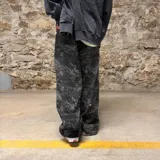 Pantalón de corte super baggy con estampado camuflado en tonos grises y negros, confeccionado en denim con efecto lavado.