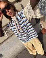 Remera de corte oversize con estampado de rayas horizontales en tonos marrón, celeste y blanco. Presenta mangas cortas con detalles de encaje tipo broderie en color crema.