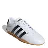 Championes Adidas modelo Grand Court Lo, de estilo urbano inspirado en el tenis. Presentan una capellada de material sintético en color blanco con las icónicas tres tiras laterales en negro y suela de goma color caramelo.