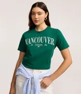 Remera de algodón color verde esmeralda con cuello redondo y mangas cortas. Presenta un estampado frontal en blanco con el texto "VANCOUVER CANADA".