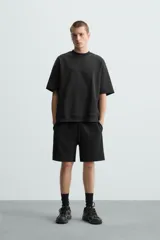 Bermuda de algodón color beige claro, corte relajado (relaxed fit), con cintura elástica ajustable mediante cordón y bolsillos laterales y trasero de plastrón.