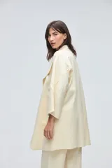 Tapado de largo medio abierto con cuello, confeccionado en lana fina sin teñir con detalles de terminación envivados en los bordes y mangas tres cuartos.