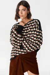 Sweater de punto con diseño geométrico de ondas en colores negro, marrón y crema. Presenta cuello redondo, mangas largas abullonadas con puños acanalados en color negro y un corte holgado.