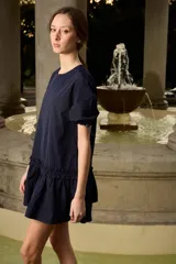 Vestido corto azul marino de corte suelto y silueta evasé, con cuello redondo, mangas cortas con regulador ajustable y detalle de volado fruncido en la parte inferior.