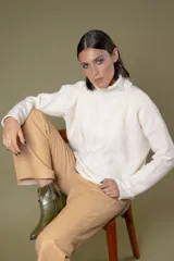 Buzo de cuello alto tejido en lana, con diseño de ochos en el centro y mangas largas con hombros caídos.