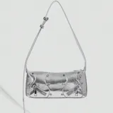 Cartera plateada tipo baguette con correa fina al hombro, detalles de tachas y cierres decorativos.