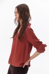 Blusa blanca de manga larga con escote en V y cuello camisero.