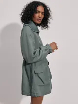 Campera larga color verde con cuello acanalado, cierre de doble sentido, bolsillos de parche grandes, cintura interior ajustable y puños con borde con volados.