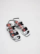 Sandalias de cuero con acabado charol color bordó, con punta cuadrada, tiras onduladas en el empeine y correa ajustable con hebilla en el tobillo. Cuentan con un taco bajo forrado.