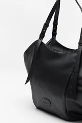 Bolso negro tipo tote de cuero sintético con acabado soft touch, asas largas regulables y diseño minimalista.