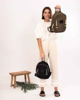 Mochila de nylon color verde oliva, con compartimento principal y bolsillo frontal con cierre metálico. Presenta detalles de cordones decorativos en los tiradores de los cierres, una grifa de goma con el logo de la marca y correas ajustables.