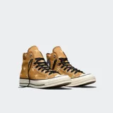 Championes Converse Chuck 70 de caña alta, color marrón con estampado de estrellas en tono crema. Presentan puntera de goma blanca, cordones negros y el icónico parche circular de la marca en el lateral.
