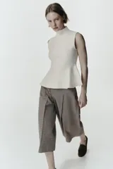 Top de punto sin mangas con cuello subido y diseño peplum con bajo evasé.
