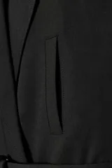 Chaleco de cuello solapa y escote en pico cruzado. Presenta diseño sin mangas con hombreras marcadas, bolsillos de vivo en el delantero y cierre frontal cruzado con botones. Incluye un cinturón de lazada en el mismo tejido para ajustar a la cintura y cuenta con forro interior.