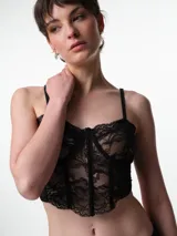 Corset de encaje negro con copas, aros y ballenas estructurales. Presenta breteles elásticos ajustables y un diseño que realza la silueta.