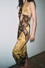 Vestido largo de viscosa con estampado floral y diseño de paneles diagonales en tonos tierra. Presenta cuello halter con cierre de botones y abertura frontal en el pecho, dejando los hombros al descubierto.