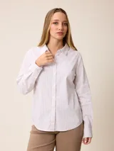 Camisa de corte clásico con cuello camisero, manga larga con puños abotonados y cierre frontal de botones. Presenta un diseño de rayas verticales finas en tonos claros.
