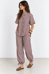 Pantalón de algodón a rayas borra de vino y blancas, de corte holgado estilo globo con cintura elástica, bolsillos laterales y detalle de ajuste con cordón en los tobillos.
