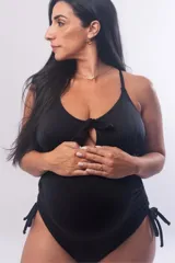 Malla entera maternal color negro, con diseño de escote con detalle de moño frontal y aberturas. Presenta frunces laterales regulables en la cadera y tiras ajustables en la espalda.