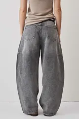 Jeans de corte barrel en tono gris deslavado, con diseño amplio y tachas decorativas a lo largo de las costuras laterales y los bolsillos delanteros.