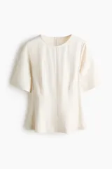 Blusa blanca de manga corta con escote redondo, costuras moldeadoras y diseño peplum acampanado con cierre trasero de botón.