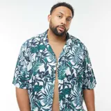 Camisa de manga corta con estampado de hojas de palmera en tonos verde, blanco y azul.